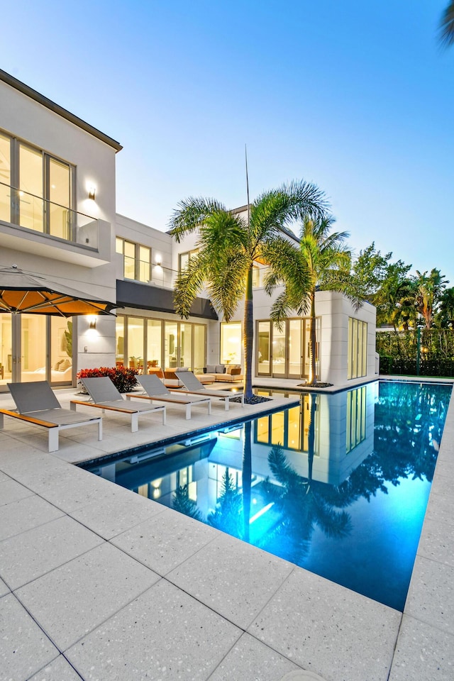 pool at dusk featuring a patio area