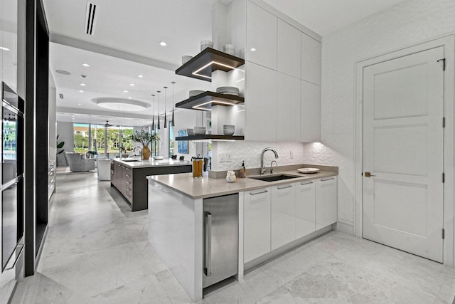 kitchen featuring pendant lighting, sink, decorative backsplash, fridge, and white cabinetry