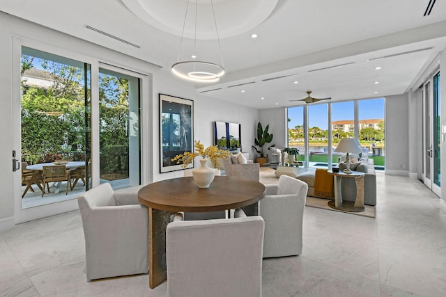 dining area with a raised ceiling, floor to ceiling windows, and ceiling fan