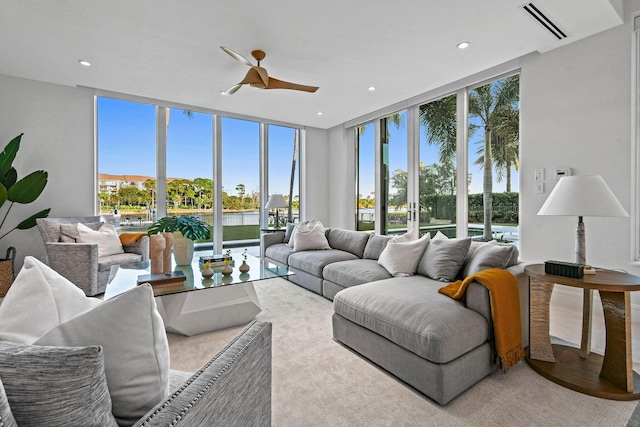 living room featuring ceiling fan and a wall of windows