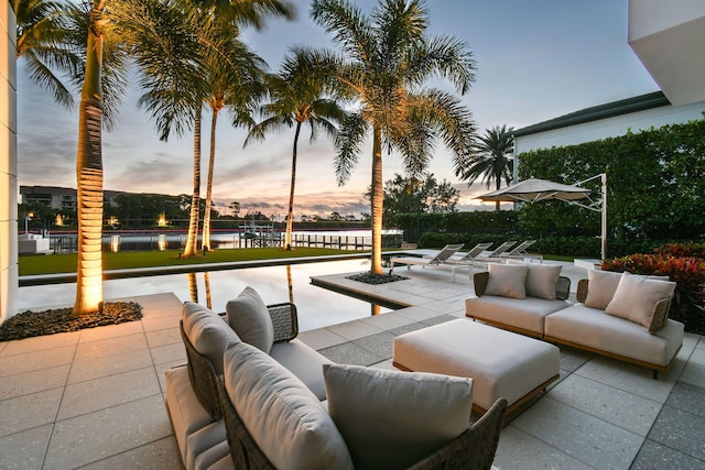 patio terrace at dusk with an outdoor hangout area and a water view