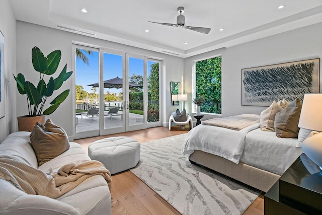 bedroom with access to exterior, ceiling fan, french doors, a raised ceiling, and light hardwood / wood-style flooring