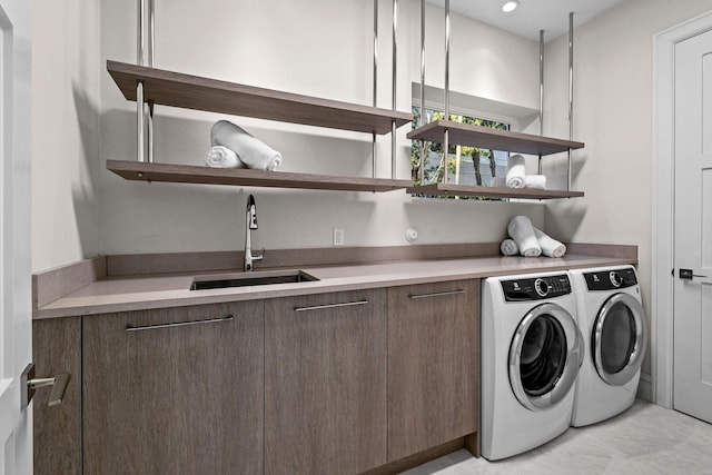 clothes washing area featuring washer and dryer, cabinets, and sink