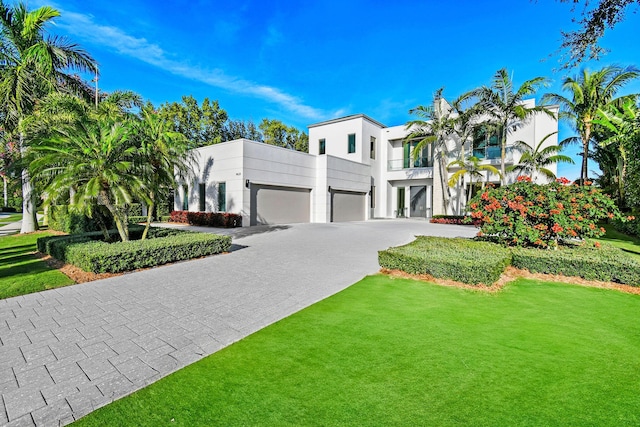 view of front of home with a front yard, a balcony, and a garage