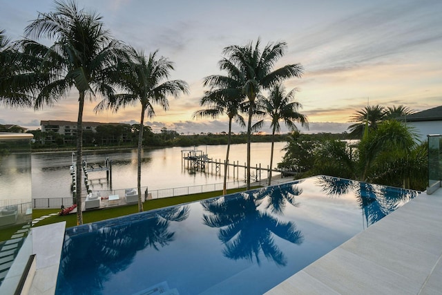 pool at dusk featuring a boat dock and a water view