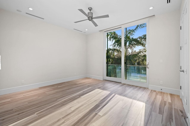 unfurnished room featuring ceiling fan, a wall of windows, and light wood-type flooring