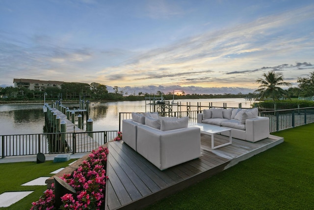 deck at dusk featuring a lawn, outdoor lounge area, a water view, and a boat dock