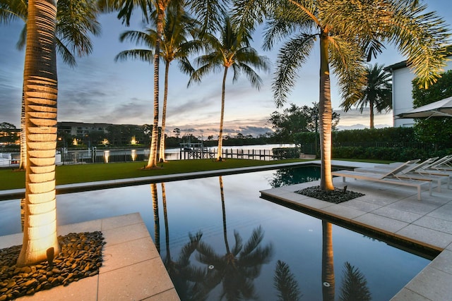 pool at dusk with a lawn and a water view