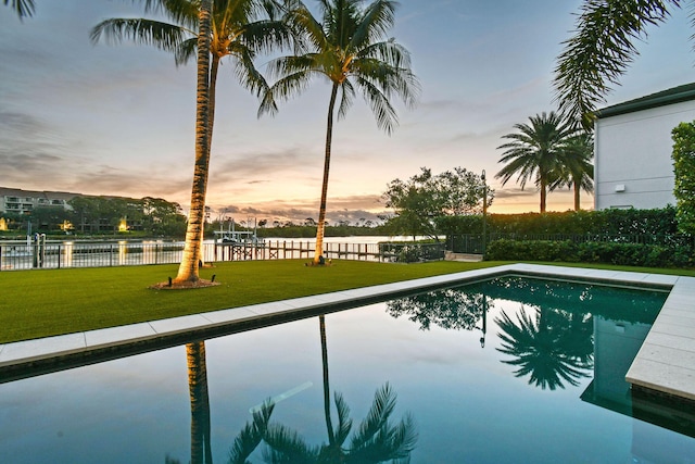 pool at dusk with a yard and a water view