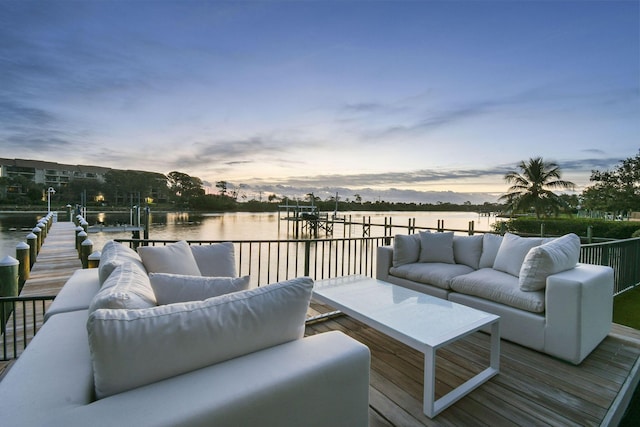 deck at dusk with outdoor lounge area, a water view, and a boat dock