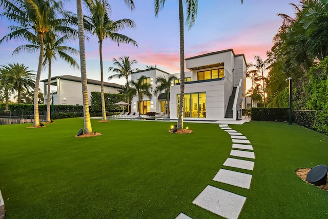 back house at dusk with a lawn