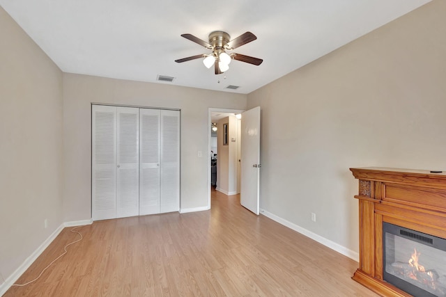 unfurnished bedroom with ceiling fan, a closet, and light hardwood / wood-style floors