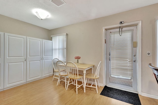 dining space with a textured ceiling and light wood-type flooring