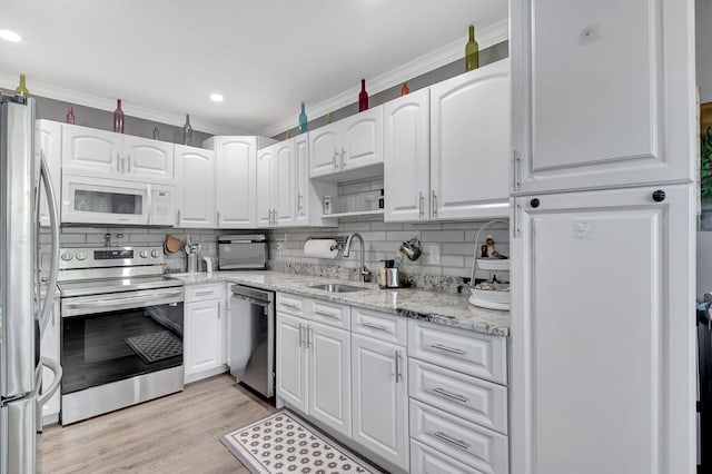 kitchen with backsplash, white cabinets, sink, light stone countertops, and stainless steel appliances