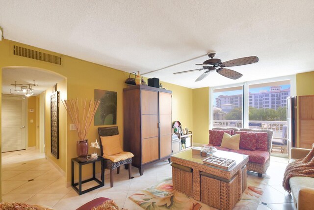 tiled living room with ceiling fan and a textured ceiling