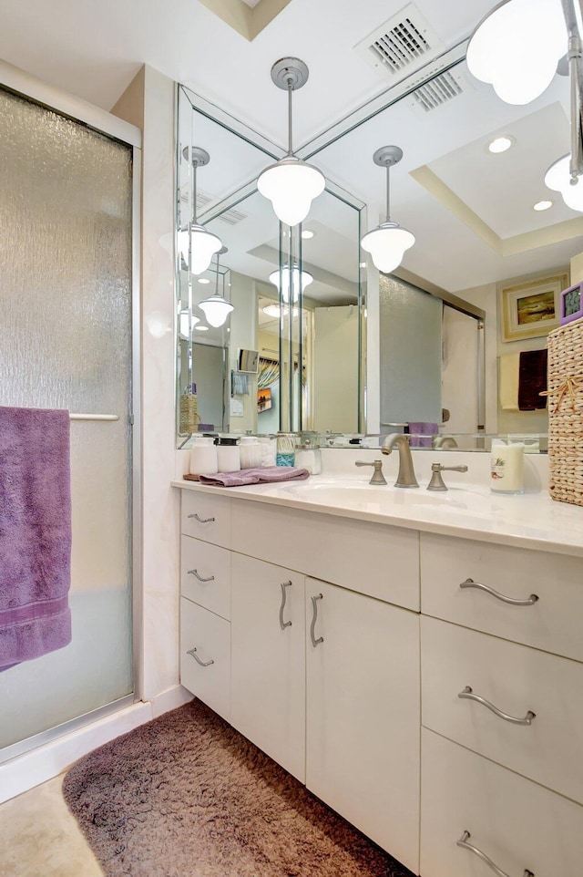 bathroom featuring a tray ceiling, vanity, and a shower with shower door