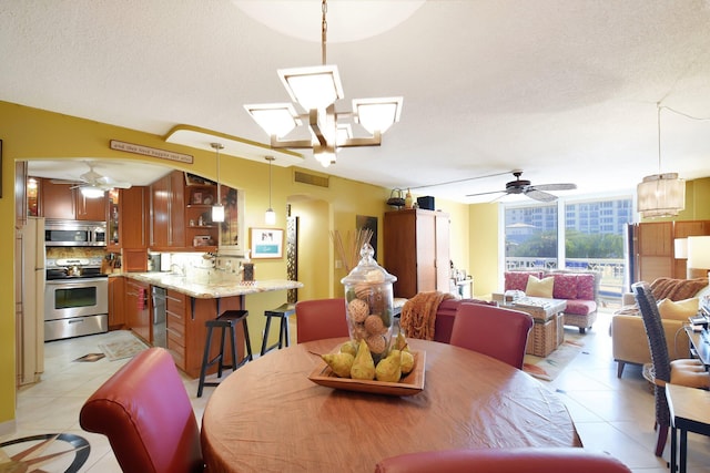 tiled dining room featuring a textured ceiling, sink, and ceiling fan with notable chandelier