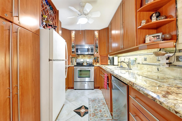 kitchen with light stone countertops, sink, ceiling fan, tasteful backsplash, and appliances with stainless steel finishes