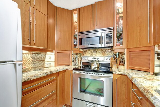 kitchen featuring light stone countertops, appliances with stainless steel finishes, and tasteful backsplash