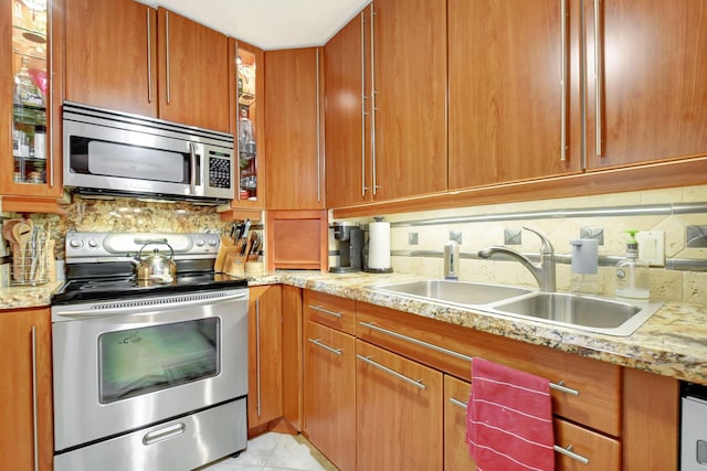 kitchen with backsplash, sink, light tile patterned floors, light stone counters, and stainless steel appliances