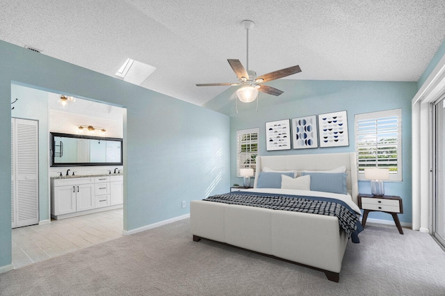 bedroom featuring lofted ceiling, ensuite bath, ceiling fan, a textured ceiling, and light carpet