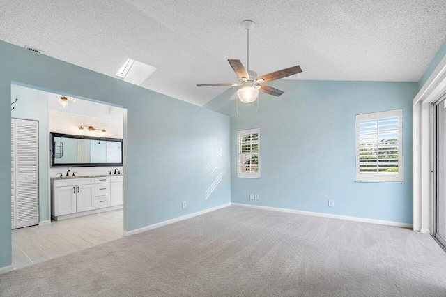 spare room featuring ceiling fan, light colored carpet, plenty of natural light, and vaulted ceiling