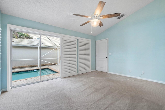 unfurnished bedroom featuring lofted ceiling, ceiling fan, a textured ceiling, and carpet flooring