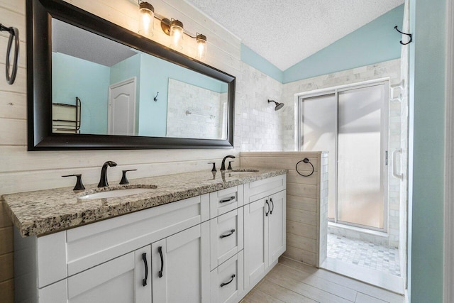 bathroom with tile walls, vanity, a shower, a textured ceiling, and vaulted ceiling