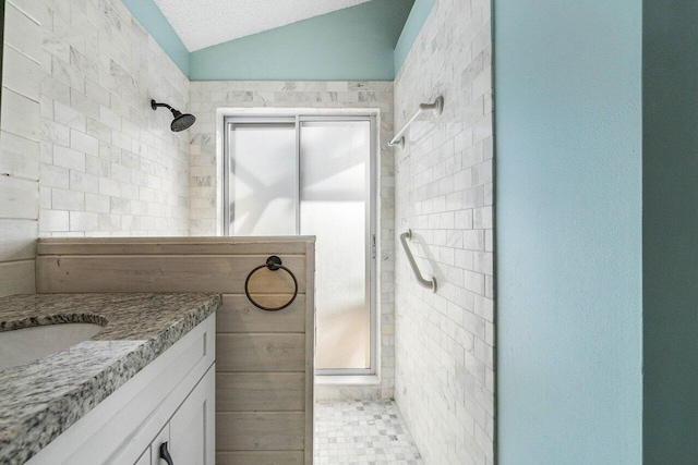 bathroom featuring vanity, lofted ceiling, and a tile shower