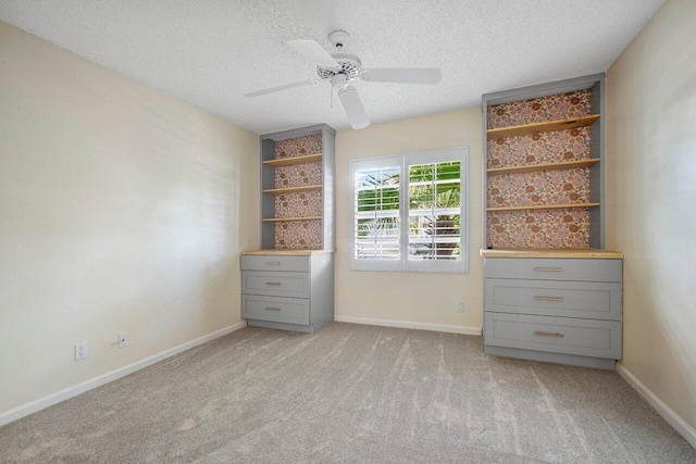 unfurnished bedroom with ceiling fan, light carpet, and a textured ceiling