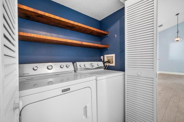 washroom featuring washing machine and dryer, a textured ceiling, and light hardwood / wood-style floors