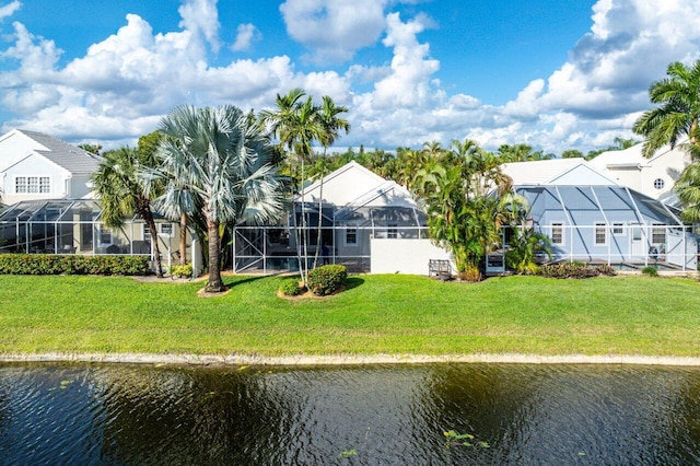 rear view of property with a yard, glass enclosure, and a water view