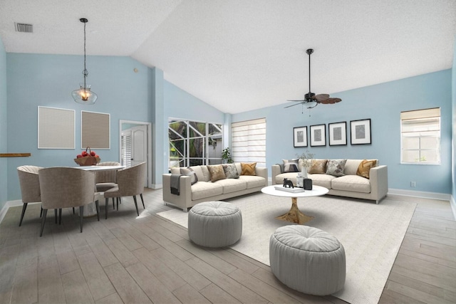 living room with a wealth of natural light, light hardwood / wood-style flooring, high vaulted ceiling, and ceiling fan