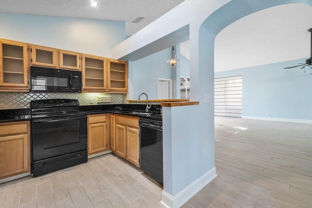 kitchen with pendant lighting, sink, light hardwood / wood-style flooring, black appliances, and decorative backsplash