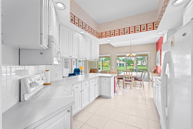 kitchen with kitchen peninsula, an inviting chandelier, white appliances, white cabinetry, and hanging light fixtures