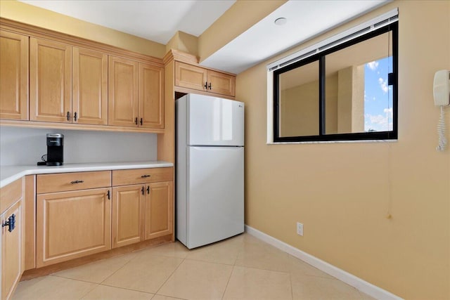 kitchen featuring light brown cabinetry, white fridge, and light tile patterned floors