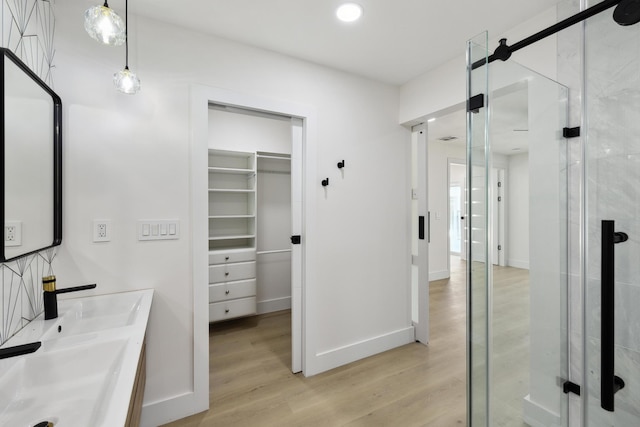 bathroom featuring wood finished floors, baseboards, recessed lighting, a stall shower, and a walk in closet