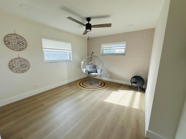interior space with baseboards, wood finished floors, and a ceiling fan