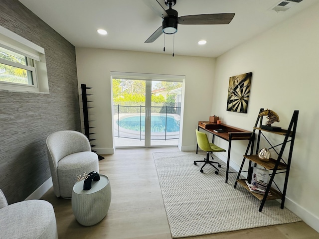 office featuring ceiling fan, visible vents, wood finished floors, and an accent wall