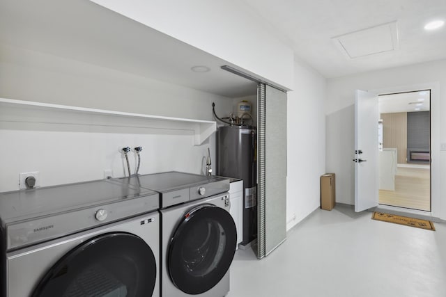 washroom with electric water heater, attic access, washing machine and dryer, and laundry area