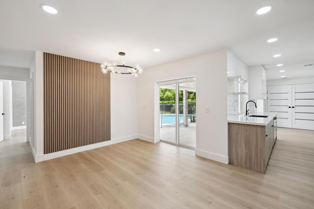 interior space featuring recessed lighting, an inviting chandelier, light wood-style flooring, and a sink