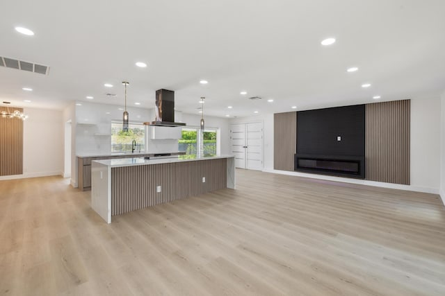 kitchen featuring visible vents, extractor fan, light countertops, light wood-style floors, and a large island