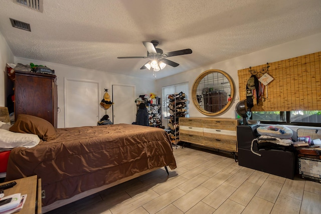 bedroom featuring wood tiled floor, a textured ceiling, visible vents, and a ceiling fan