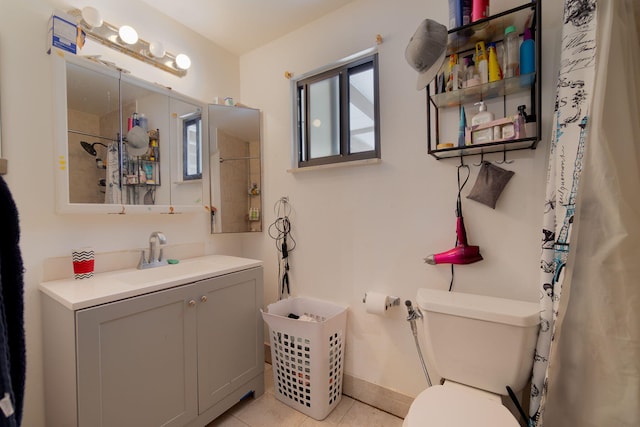 bathroom featuring tile patterned flooring, toilet, vanity, baseboards, and a shower