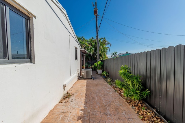 view of side of home with fence private yard, a patio area, stucco siding, and central AC unit