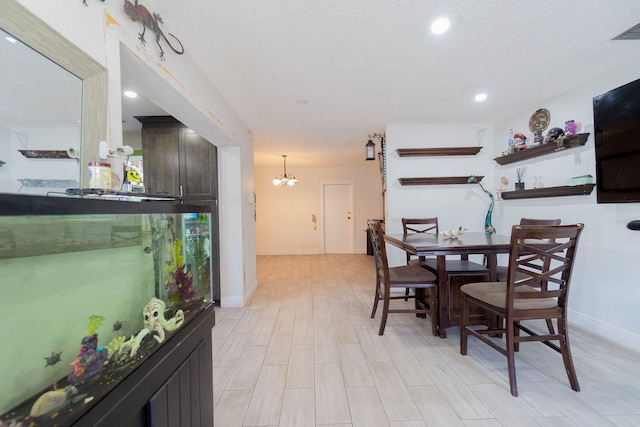 dining area with a textured ceiling, baseboards, visible vents, and a notable chandelier