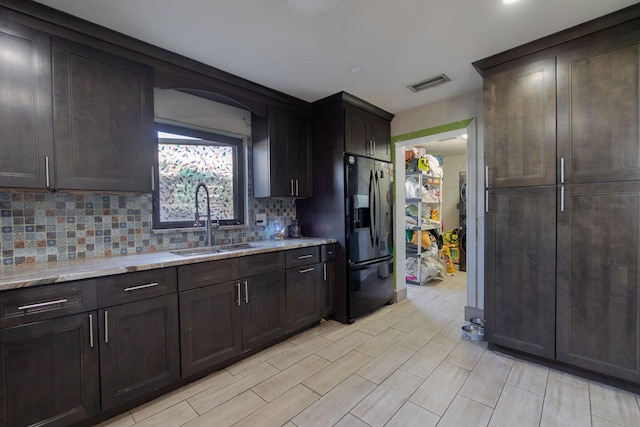 kitchen with dark brown cabinetry, a sink, visible vents, decorative backsplash, and black refrigerator with ice dispenser