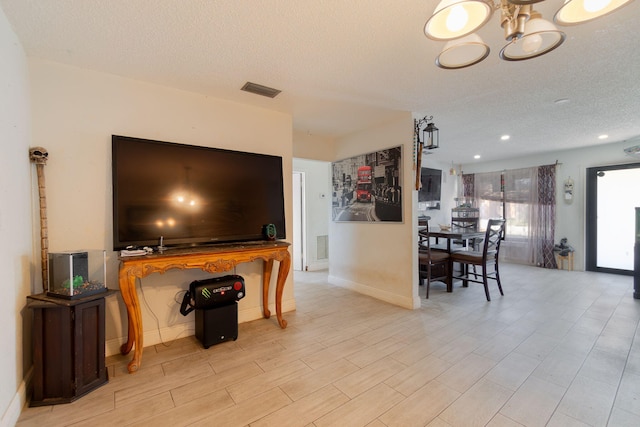 living room featuring recessed lighting, visible vents, an inviting chandelier, a textured ceiling, and baseboards