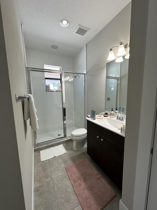 bathroom featuring vanity, toilet, an enclosed shower, and a textured ceiling