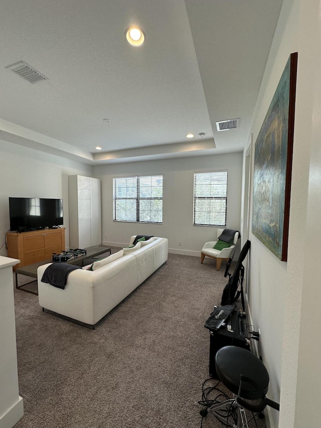 living room with a tray ceiling and carpet floors